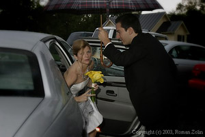Groom is helping the bride out of a car
